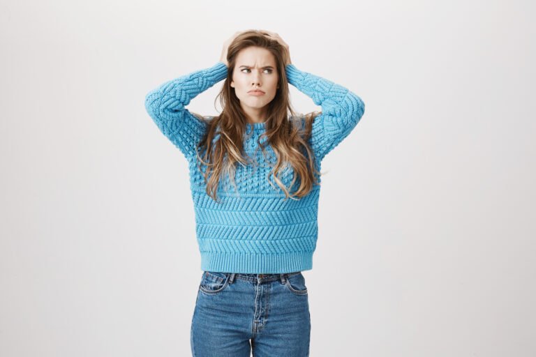 indoor shot of clueless determined caucasian woman holding hands on head and looking up with puzzled expression as if she thinks or forgot something, standing over gray background. did i closed door